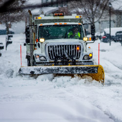 Snow plow pushing snow off the road with a yellow plow