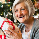 Older woman happily receives a wrapped Christmas gift