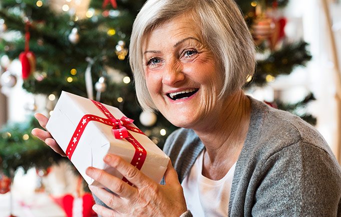 Older woman happily receives a wrapped Christmas gift